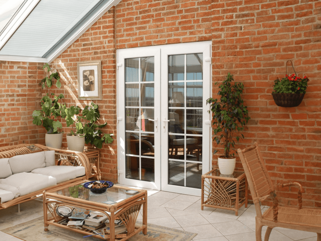 French doors vs sliding glass doors: Which suits your space? 3 white upvc patio door on the back of a modern red brick home leading to a well lit conservatory